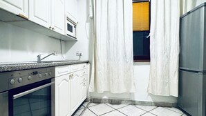 Eine Küche mit weißen Schränken, einem eingebauten Backofen, einer Mikrowelle und einem Edelstahl-Kühlschrank.