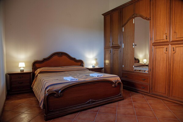 Une chambre à coucher avec un lit en bois, deux tables de chevet avec des lampes et une grande armoire.