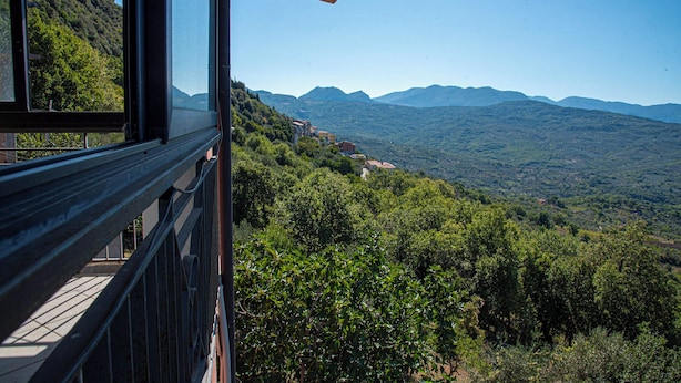 A scenic view from a balcony overlooking a lush valley with mountains in the distance.