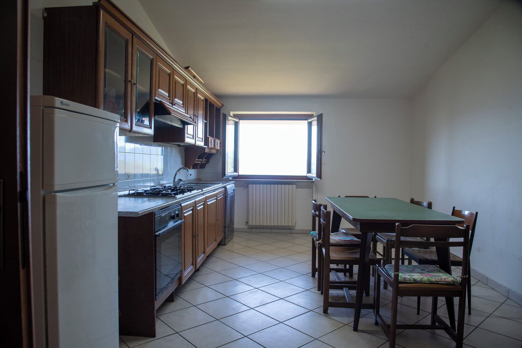 A kitchen with wooden cabinets, a stove, and a dining table with chairs.