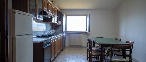 A kitchen with wooden cabinets, a stove, and a dining table with chairs.