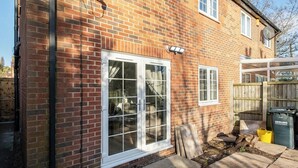 A brick house with a white-framed window and a door, a wooden fence, and a garden area with a trash bin labeled "CEDLING." - CircleWay Homes - Colwick (Colwick)