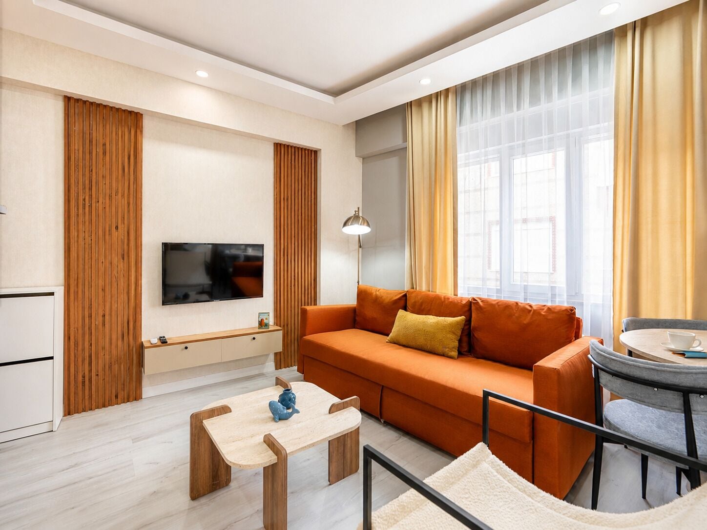A modern living room with a sofa, a coffee table, a TV, and a lamp.