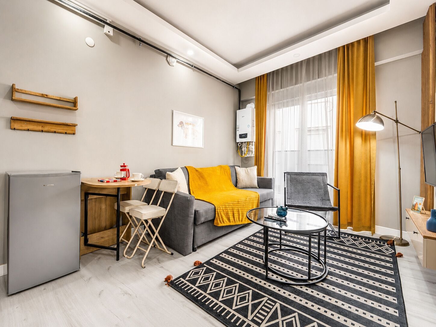 A modern living room with a sofa, coffee table, and a small dining area.