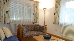 En hyggelig stue med en sofa, et træ sofabord og en gulvlampe.
