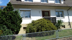 Et toetagers hus med mange vinduer, en synlig skorsten og en lille balkon.