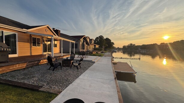 En ejendom ved søen med terrasse, udendørs møbler og en badebro.