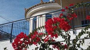Ein Gebäude mit weißer Fassade, blauen Geländern und roten Blumen davor.