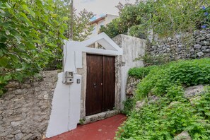 A narrow entrance with a wooden door, a white wall, and a stone wall. - Kalimera Loft I – Village Experience ,a cozy retreat (Argiroupoli)