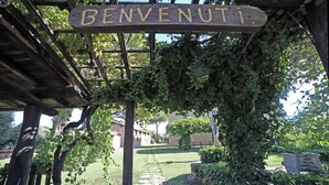A wooden pergola with a sign reading "BENVENUTI" in a garden setting. - Apartment with pool in a family farmhouse on the Tuscan coast. (Castagneto Carducci)