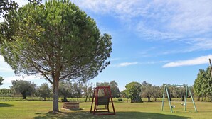 A park with a swing set and a large tree. - Apartment with pool in a family farmhouse on the Tuscan coast. (Castagneto Carducci)