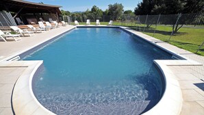A rectangular swimming pool with a circular hot tub in the center, surrounded by lounge chairs and a covered seating area. - Apartment with pool in a family farmhouse on the Tuscan coast. (Castagneto Carducci)