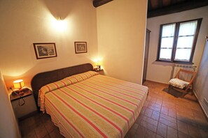 A bedroom with a bed, bedside lamps, a chair, and a window. - Apartment with pool in a family farmhouse on the Tuscan coast. (Castagneto Carducci)