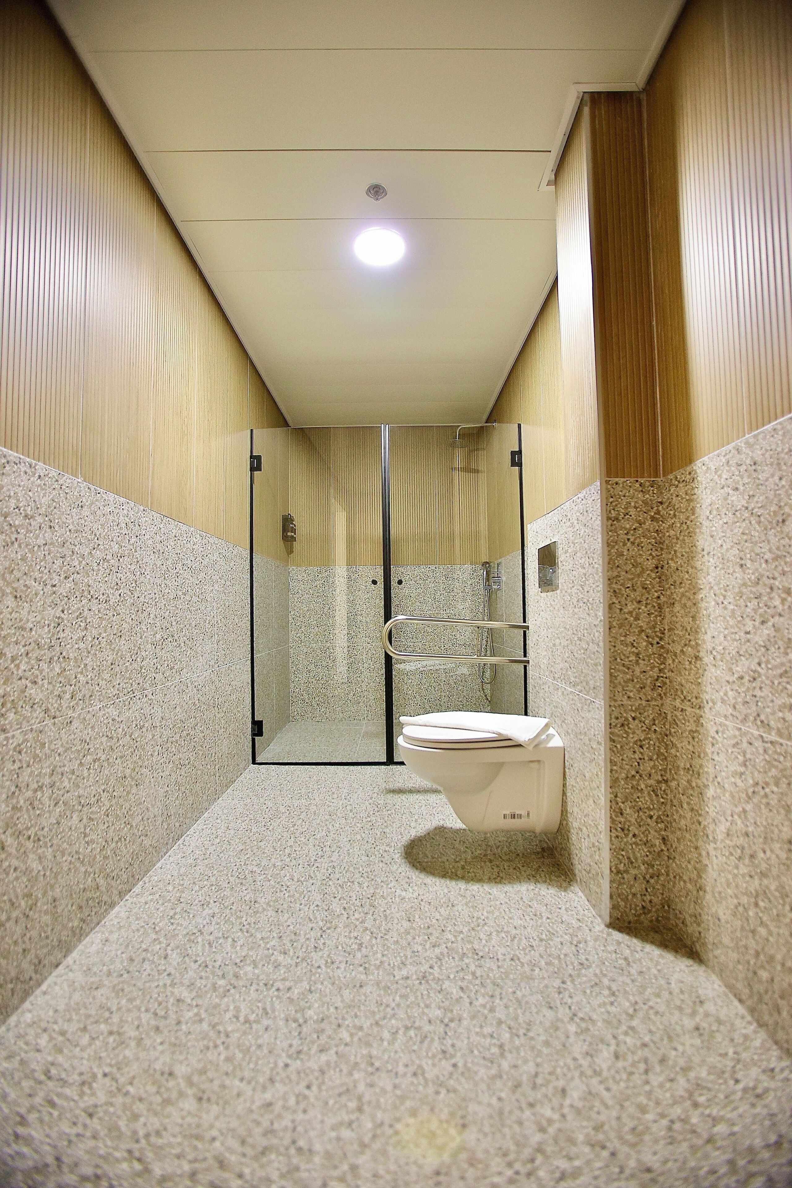 Un baño moderno con cabina de ducha de vidrio, inodoro y suelo de baldosas.