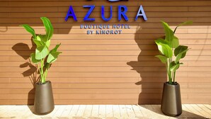A sign for 'AZURA Boutique Hotel by Kinorot' with two potted plants in front. - Azura Boutique Hotel (Tiberias)