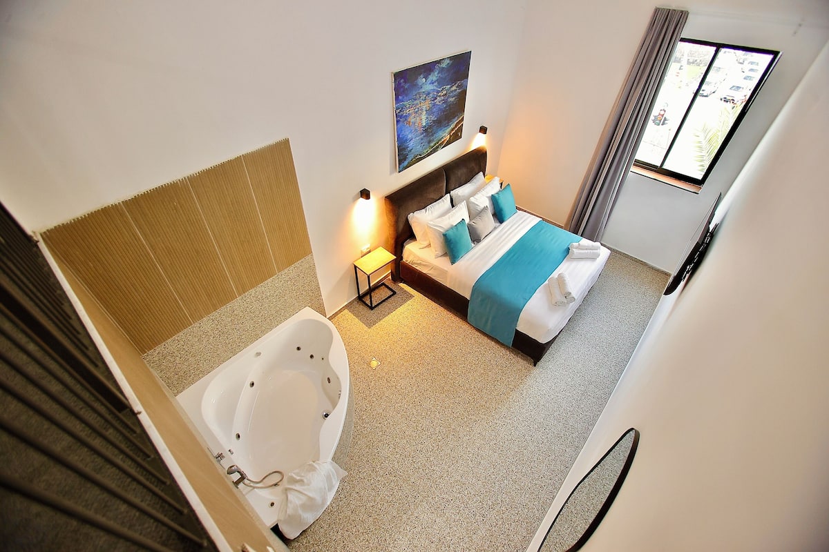 Una habitación de hotel con una cama grande, una bañera y un cuadro en la pared.