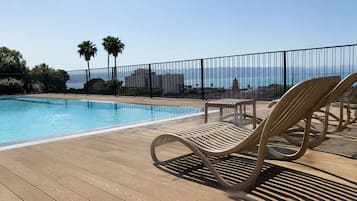 Una piscina al aire libre de temporada, tumbonas