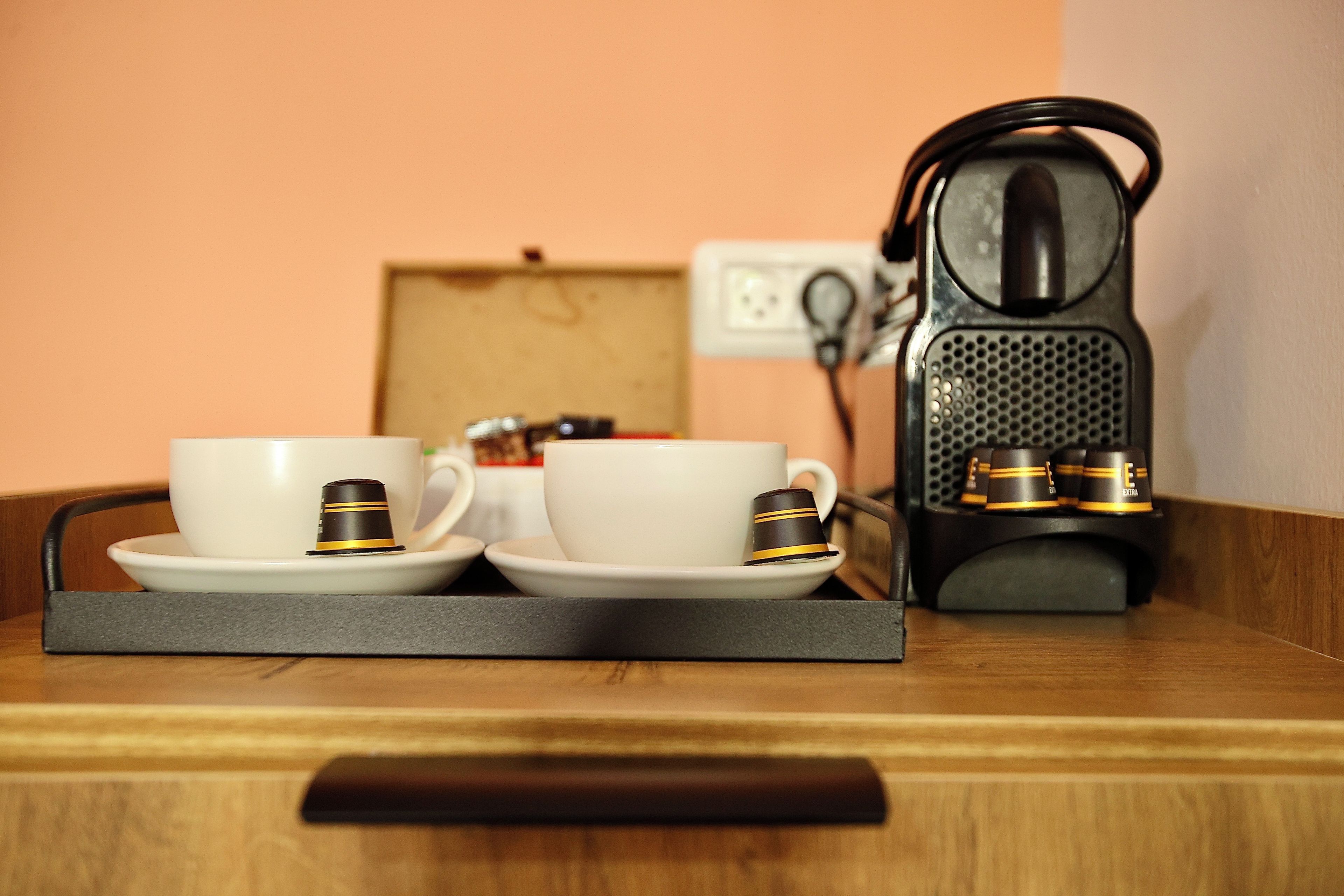 Una cafetera sobre una mesa con dos tazas blancas y una bandeja.