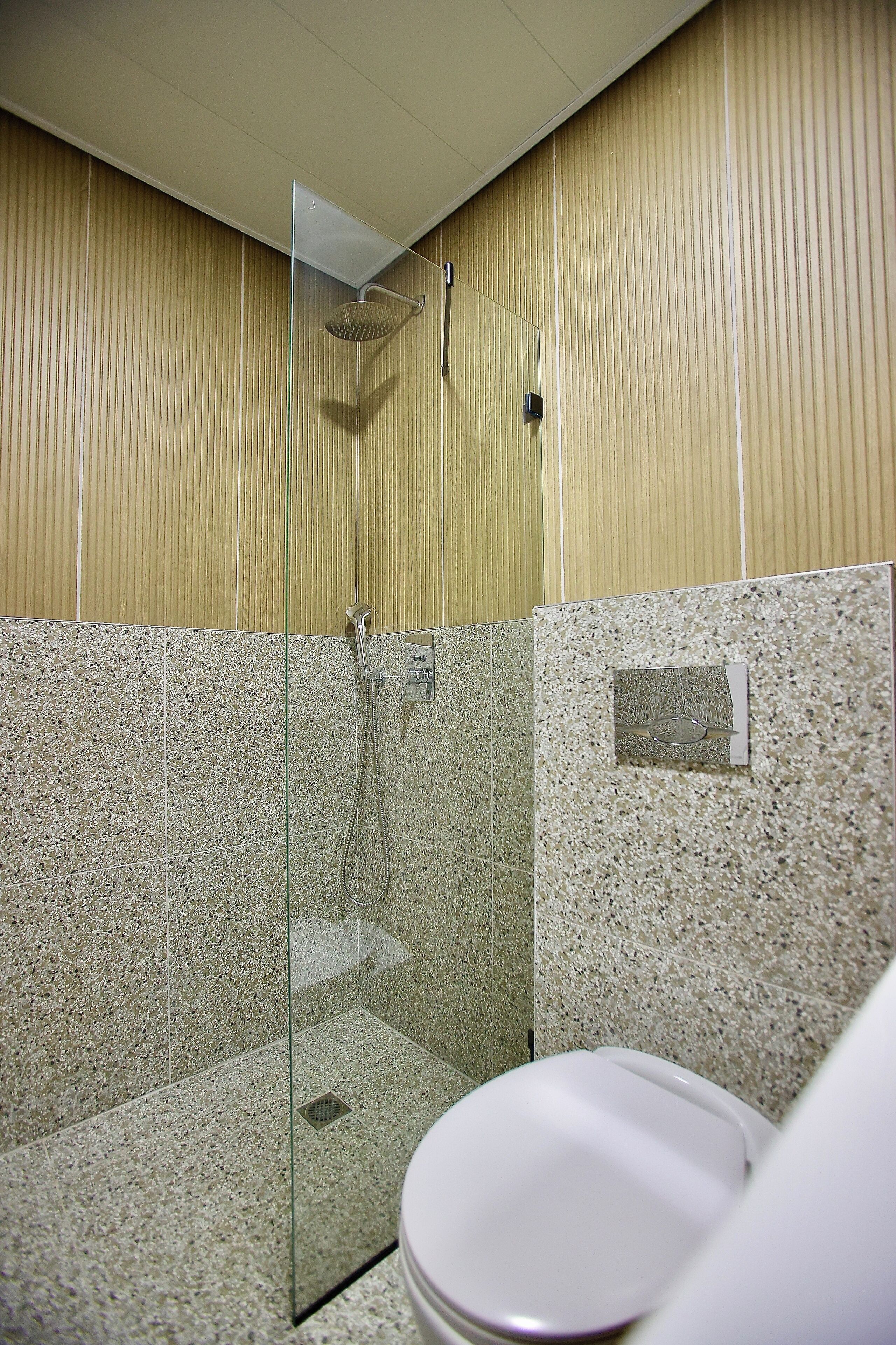Un baño con ducha, inodoro y paredes de azulejos.