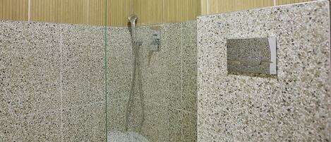 Un baño con ducha, inodoro y paredes de azulejos.
