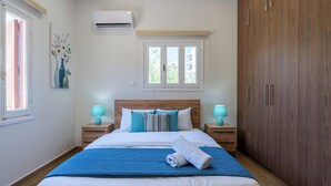 Une chambre dotée d’un grand lit, de deux tables de chevet avec des lampes, d’une armoire, d’une fenêtre offrant une vue agréable et d’un appareil de climatisation.