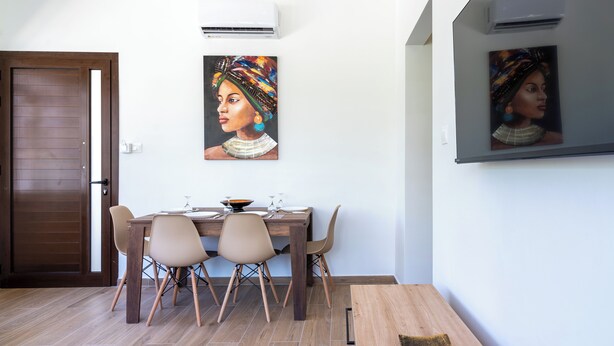 Un coin repas avec une table en bois, quatre chaises et deux tableaux accrochés au mur.