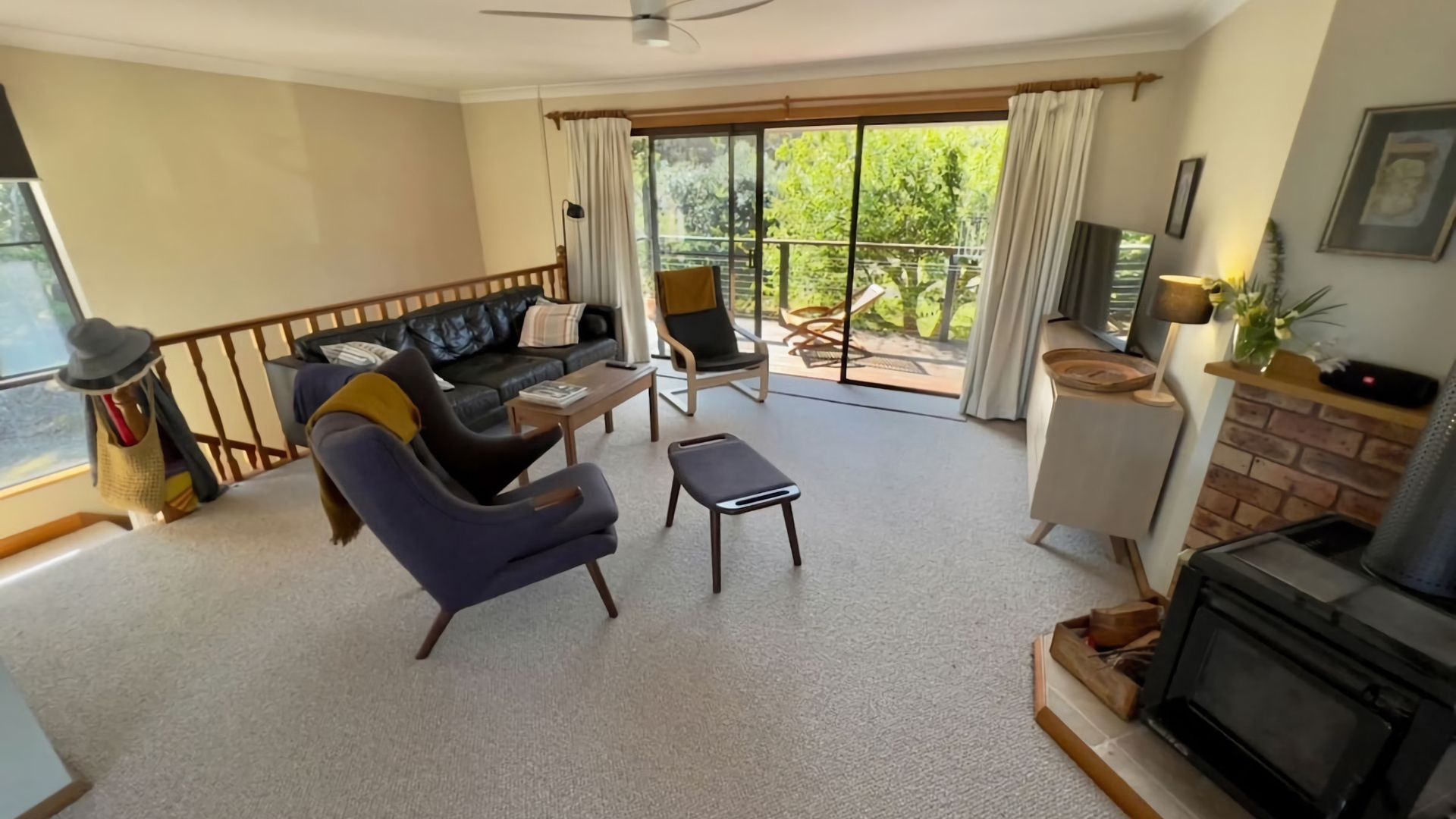 Een woonkamer met een bank, fauteuil, salontafel en een open haard.