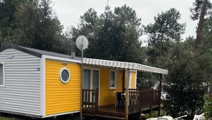A mobile home with a porch, a satellite dish, and a number '141' on the side. - Mobile home in La Palmyre, 10 minutes from the beach, close to the zoo and the Coubre lighthouse (Les Mathes)