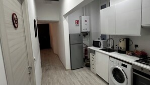 A compact kitchen with a washing machine, microwave, and a small refrigerator. - Nalusa rooms - in downtown Toledo (Napoli)