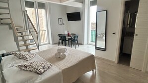 A spacious bedroom with a large bed, a dining table, and a TV mounted on the wall. - Nalusa rooms - in downtown Toledo (Napoli)