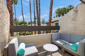 A patio with a gray sofa, a round table, and a wooden pergola. - @ Marbella Lane - Gem w/ Outdoor Fun Pool & Trails (Palm Springs)