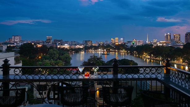 A cityscape at dusk with a river and buildings in the background. - Hoan Kiem Legend Ha Noi Hotel (Hanoi)