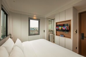 Une chambre d’hôtel avec un lit, un téléviseur fixé au mur diffusant Netflix, une fenêtre avec vue et une porte.