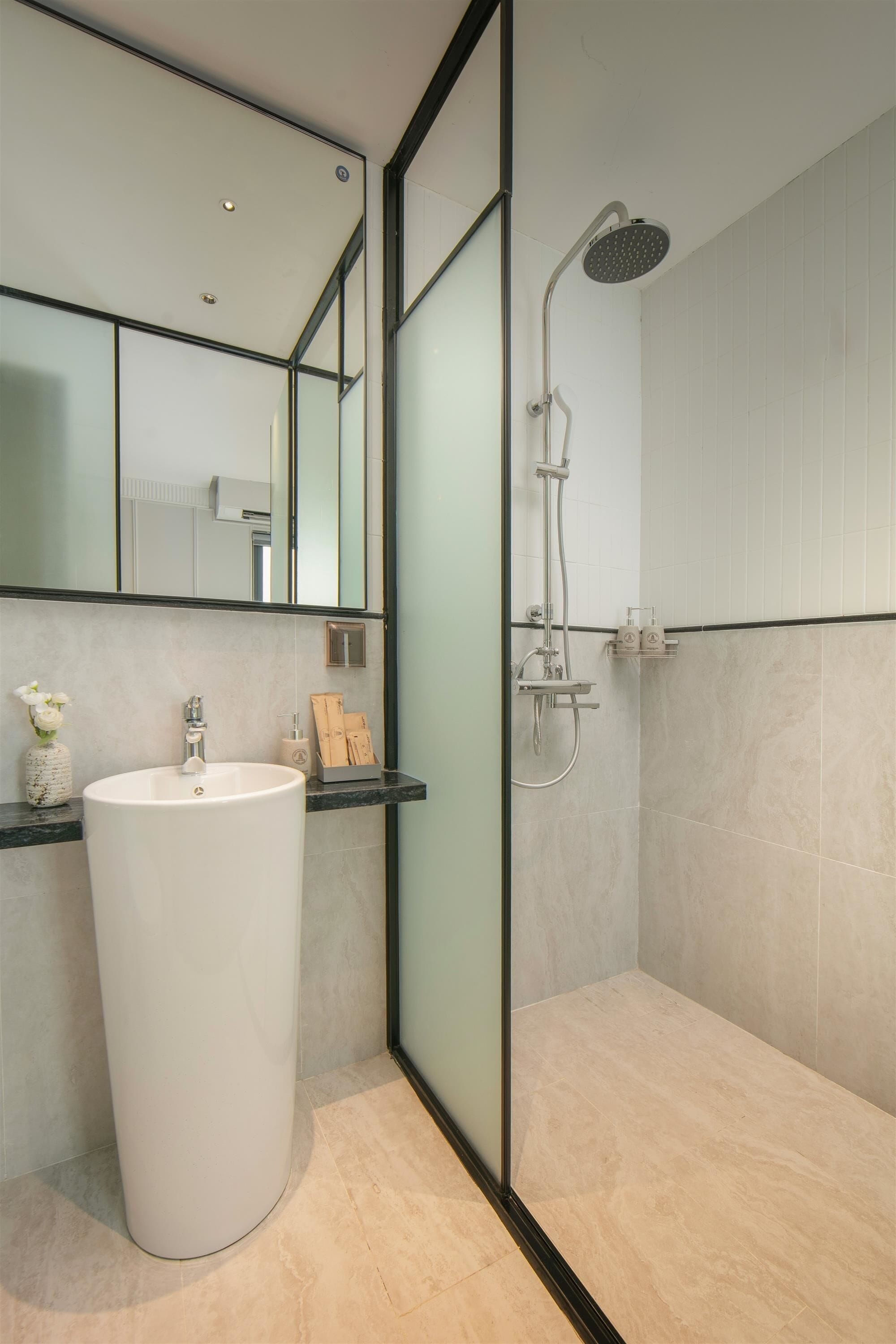 Une salle de bain moderne avec un grand lavabo blanc, une cabine de douche en verre et un miroir au-dessus du lavabo.