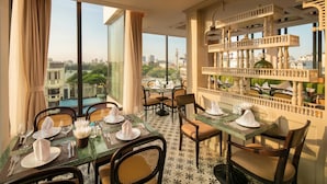 A dining area with tables set for four, large windows with curtains, and a balcony with a railing. - Hoan Kiem Legend Ha Noi Hotel (Hanoi)