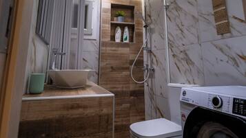 Un baño pequeño con ducha, inodoro y lavadora.