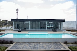 En moderne bygning med en swimmingpool foran.