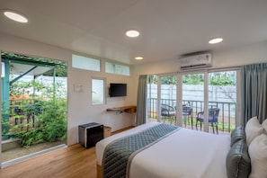 Une chambre d’hôtel avec un lit, une télévision, un bureau et un balcon équipé de chaises.