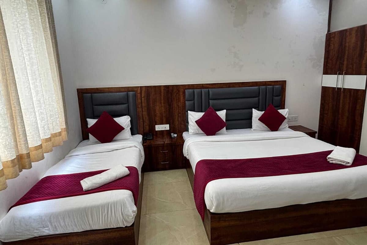 A hotel room with two beds, each with a wooden headboard, white bedding, and red throw pillows.