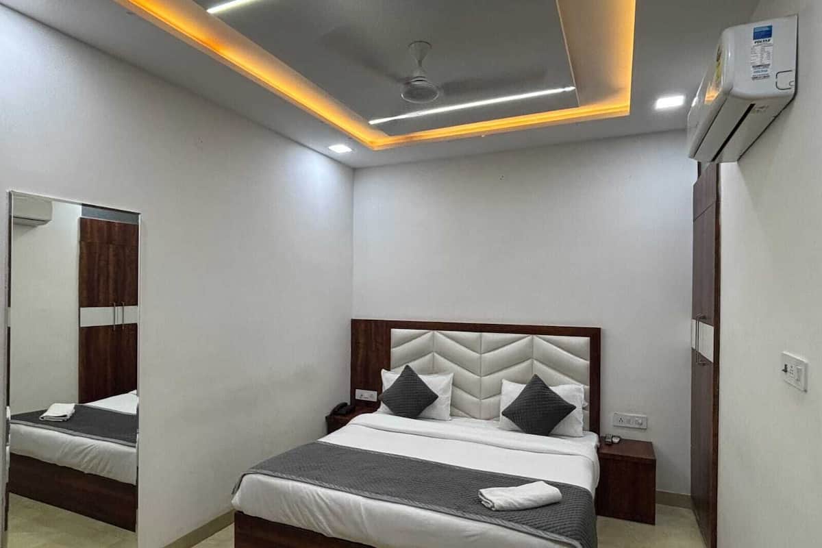 A modern bedroom with a bed, bedside tables, a mirror, and an air conditioning unit.