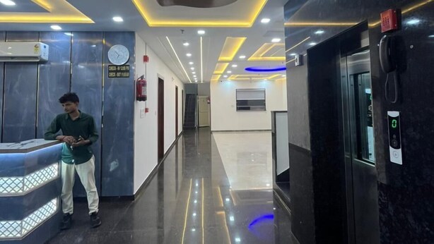 A modern lobby with a reception desk, elevators, and a clean, reflective floor. - Hotel Ganga Palace (Agra)