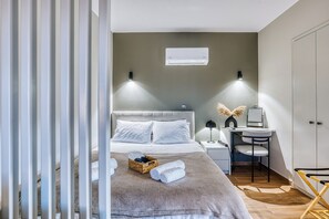 A modern bedroom with a bed, bedside table, and a desk with a chair.