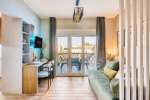 Una sala de estar moderna con un sofá, una mesa de comedor y un televisor montado en la pared.