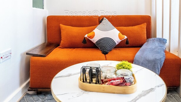 Un salon chaleureux avec un canapé orange, une table basse ronde et des coussins décoratifs.