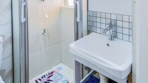 Une salle de bain moderne avec une douche à parois de verre, un lavabo blanc et un sol carrelé.