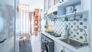 Une cuisine moderne avec des armoires blanches, un évier en acier inoxydable et des carreaux décoratifs sur le mur derrière l’évier.