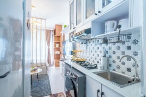 Eine moderne Küche mit weißen Schränken, einer Edelstahl-Spüle und Fliesen mit Muster.