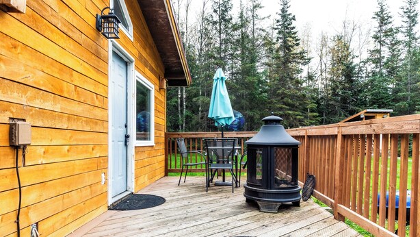 A wooden deck with a wood-burning stove, outdoor furniture, and a door. - Perfect 3-bedroom house in Hope for a relaxing getaway (Hope)