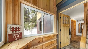 A wooden interior with a bench, a sliding glass door, and a sign that says "UNLOAD HERE".
