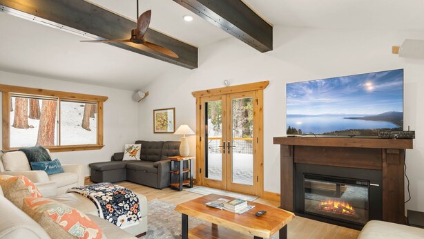 A cozy living room with a fireplace, a large TV, and a view of the outdoors.